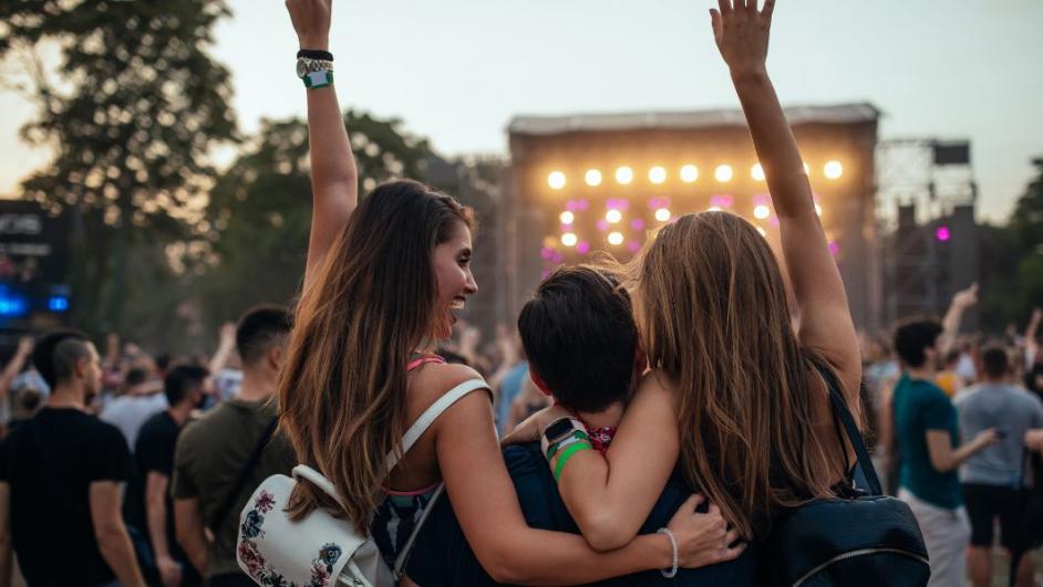 Un gruppo di ragazze e ragazzi di abbraccia durante un festival musicale