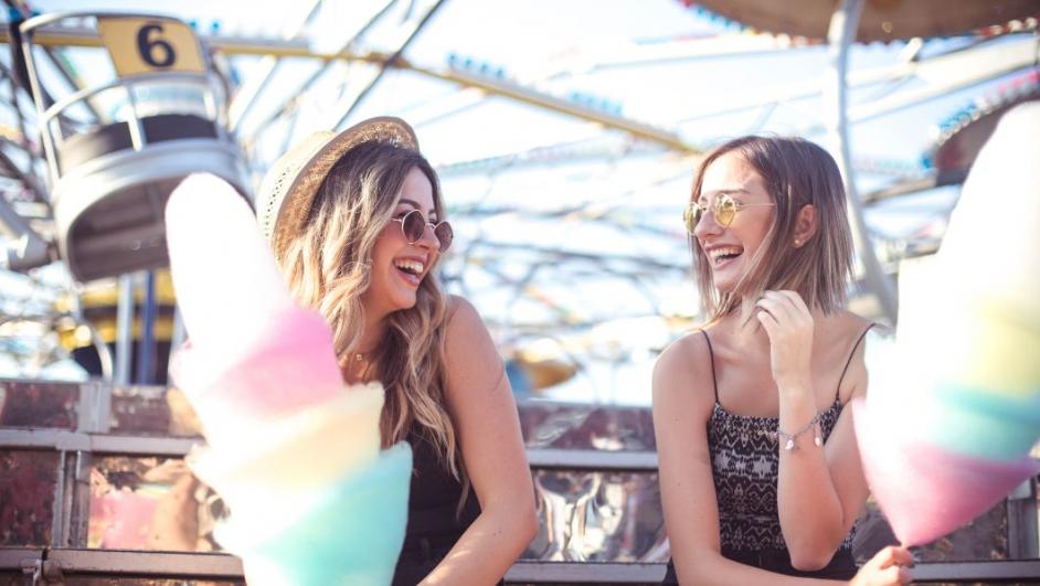 due ragazze in un parco di divertimento mangiano zucchero filato