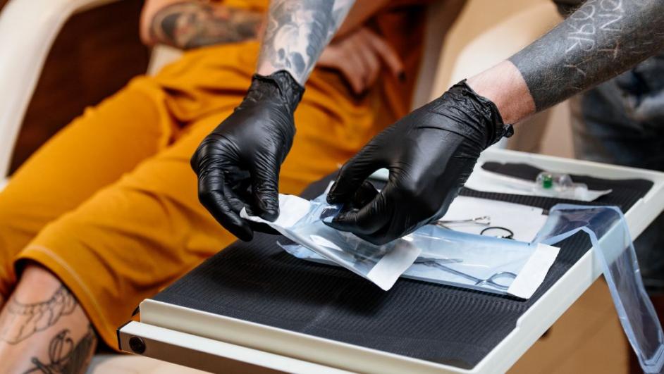 Tatuatore apre gli strumenti per eseguire il tatuaggio su un ragazzo